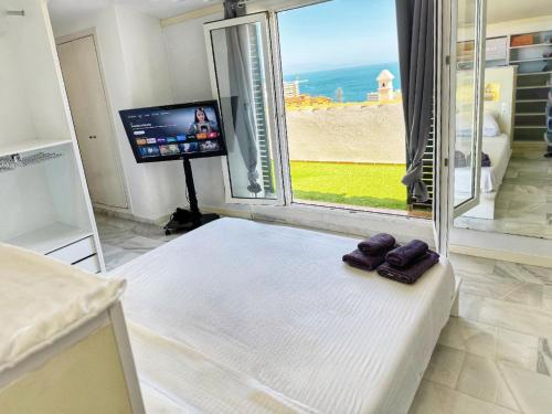 a bedroom with a bed and a tv and a window at Duplex Penthouse with Seaview. in Benalmádena