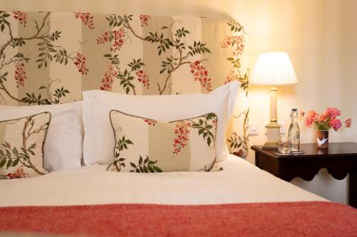 a bedroom with a bed with white sheets and flowers at Ballymaloe House Hotel in Ballycotton