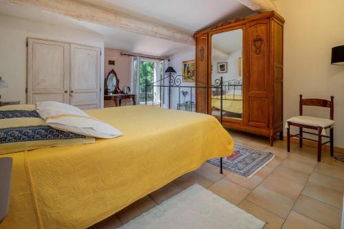 a bedroom with a yellow bed and a balcony at Clos des Hérissons - Chambres d'Hôte - Piscine & jardin in Lauris