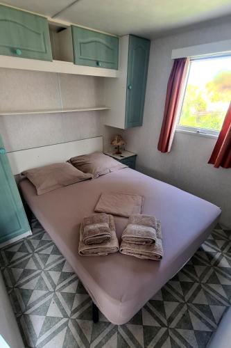 - un grand lit dans une chambre avec des serviettes dans l'établissement Mobil-home sur terrain privé bord de mer, parking privé, au Grau-dʼAgde