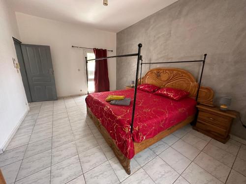 a bedroom with a bed with a red comforter at Villa du Bonheur in Sali Nianiaral
