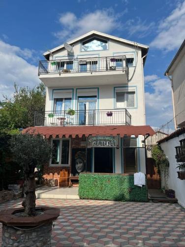 a white building with a balcony on top of it at Kultura Hostel in Shkodër