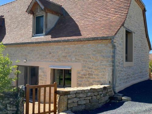 a brick house with a wooden fence in front of it at Location saisonnière in Alvignac
