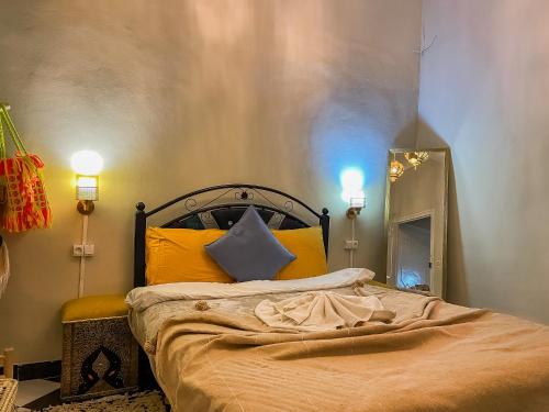 1 dormitorio con cama con almohadas amarillas y espejo en Noubti en Marrakech