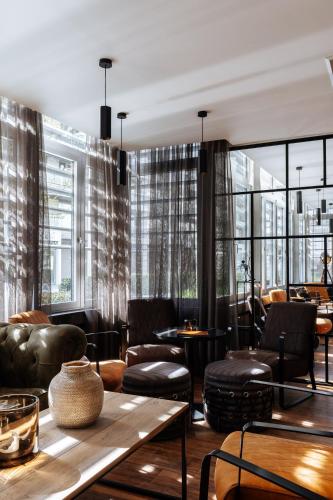 a restaurant with leather furniture and large windows at Cosmopolite Hotel Nieuwpoort-Bad in Nieuwpoort