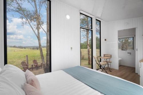 a bedroom with a bed and a large window at The Stockmans Camp 1 - Sunset Tiny House in Buchan