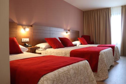 Habitación de hotel con 2 camas con almohadas rojas en HOTEL ARZÚA, en Arzúa