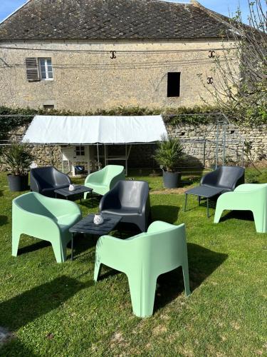 a group of chairs and tables in the grass at Hôtel Restaurant le clos de l 'Ancien Pressoir in Commes