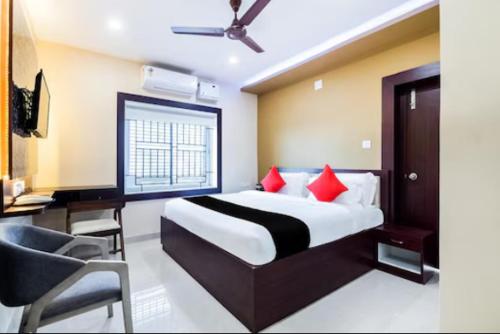 a bedroom with a bed with red pillows and a chair at 107 NOTOUT in Bhubaneshwar