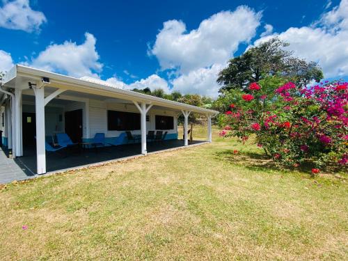 a white house with a yard with flowers at Villa Créole vue sur mer des Caraïbes in Le Carbet