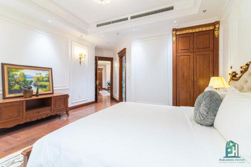 a bedroom with a white bed and a wooden cabinet at Luxe Paradise Suite Hotel Trich Sai in Hanoi