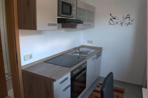 eine kleine Küche mit einer Spüle und einer Mikrowelle in der Unterkunft Ferienwohnung Hüttinger/Summer in Pappenheim