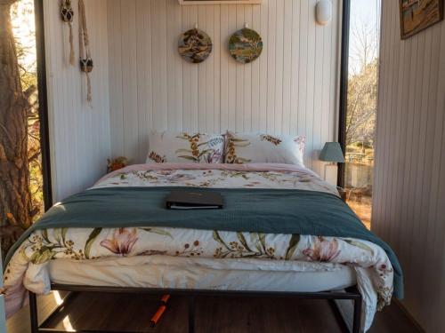 a bedroom with a bed with a green comforter at Blue Gum at Aranya Acres in Bungendore