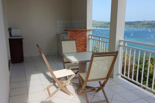 einen Tisch und Stühle auf einem Balkon mit Blick auf das Wasser in der Unterkunft Studio du PARADIS in Le Marin