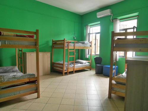 a room with three bunk beds and a green wall at Kultura Hostel in Shkodër