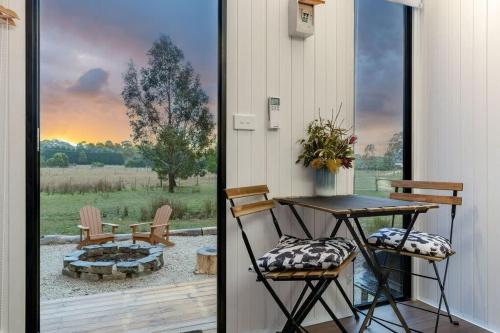 a patio with a table and chairs and a fire pit at Left Field Tiny House in Ashbourne