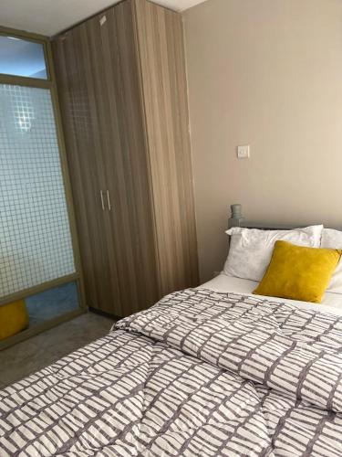 um quarto com uma cama com uma almofada amarela e uma janela em Lulu’s staycations Tsavo em Nairobi