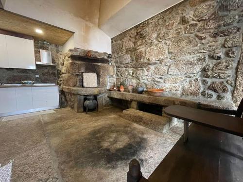 a kitchen with a stone wall with a stone fireplace at Casa do Capitão de Cutelo - Gerês in Terras de Bouro
