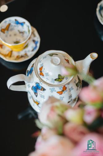 a teapot and a cup on a table with flowers at Luxe Paradise Suite Hotel Trich Sai in Hanoi