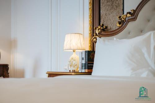 a bedroom with a bed with a lamp and a mirror at Luxe Paradise Suite Hotel Trich Sai in Hanoi