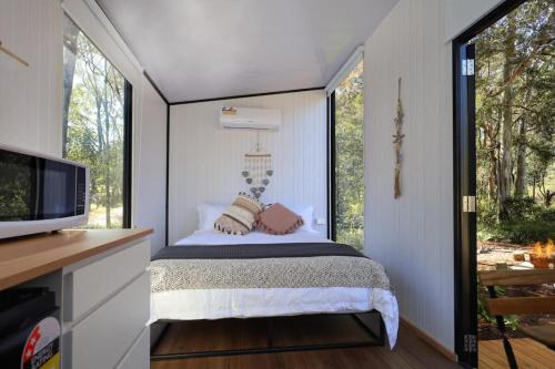 a small bedroom with a bed and a window at Silveroak Lodge Tiny House 