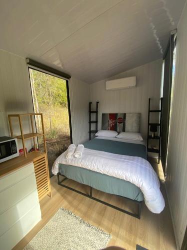 1 dormitorio con 1 cama en una casa pequeña en Hill Creek 2 Tiny House, en Perwillowen