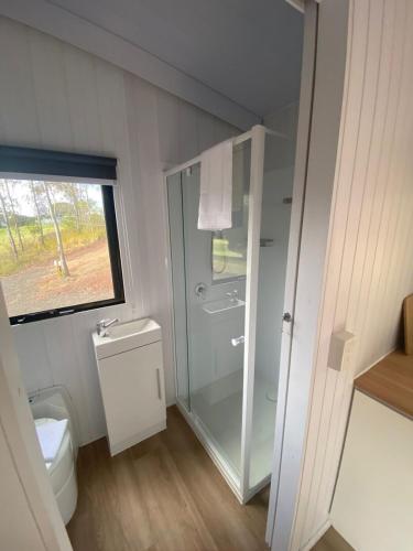 a bathroom with a glass shower and a toilet at Hill Creek 2 Tiny House in Perwillowen