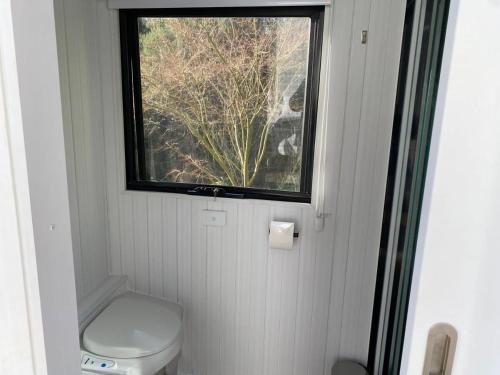 a small bathroom with a toilet and a window at The Whistling Frog in Neerim South