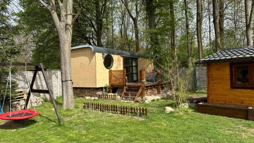 eine Hütte im Wald mit einer Schaukel und einem Spielplatz in der Unterkunft Maringotka Trojzemka in Hrádek nad Nisou