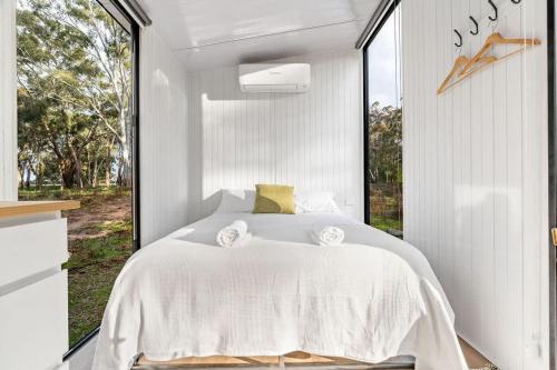 a bedroom with a white bed and a large window at Northern Grampians Getaway in Dadswells Bridge
