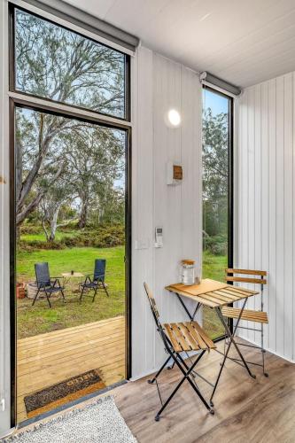 a room with a table and chairs and a large window at Northern Grampians Getaway by Tiny Away in Dadswells Bridge