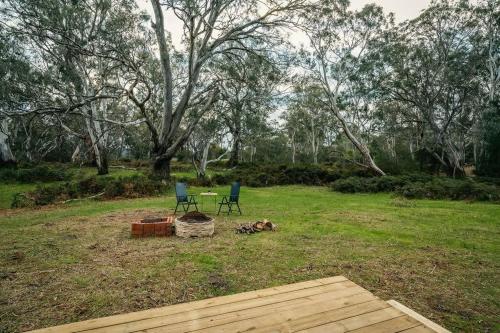 two chairs and a table in a field with trees at Northern Grampians Getaway by Tiny Away in Dadswells Bridge