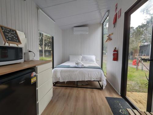 a small bedroom with a bed in a tiny house at Tiny House 3 at Grampians Edge in Dadswells Bridge
