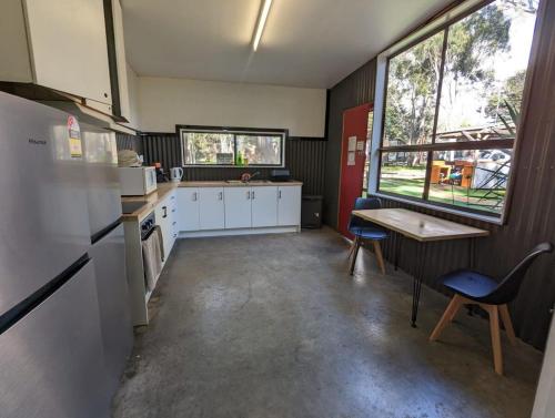 a kitchen with white cabinets and a table and chairs at Tiny House 5 at Grampians Edge in Dadswells Bridge