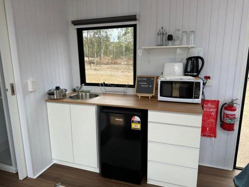 cocina con nevera negra y microondas en The Retreat Tiny House 2, en Lagoon Pocket