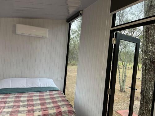 a bedroom in a trailer with a bed and a window at 5 Acre Retreat in Jimboomba