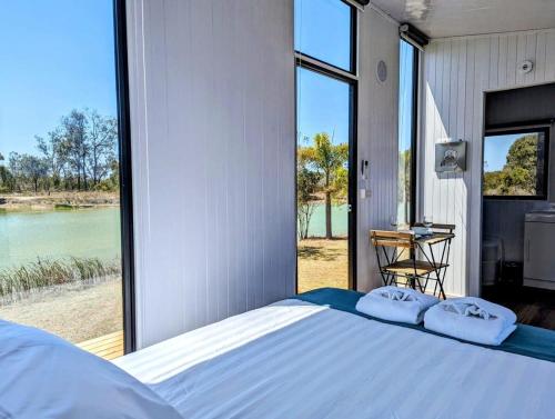 sypialnia z łóżkiem i dużym oknem w obiekcie Turtle Island Lakeside Tiny House w mieście Toogoom