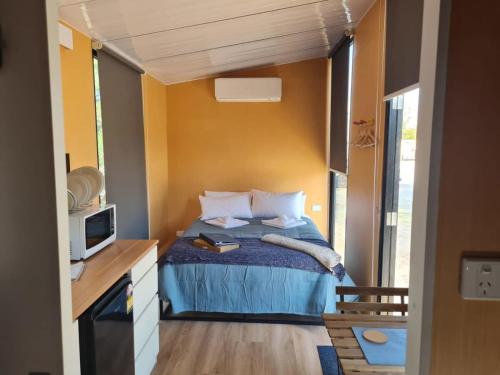 een kleine slaapkamer met een bed en een televisie bij Alma's Tiny House in Willunga