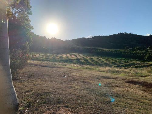 a field with the sun setting in the background at Tiny House Elevation 156-2 in Amamoor