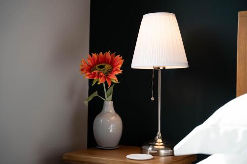 un jarrón con una flor en una mesa junto a una lámpara en Park View- 2 bed apartment close to East Surrey Hospital, en Salfords