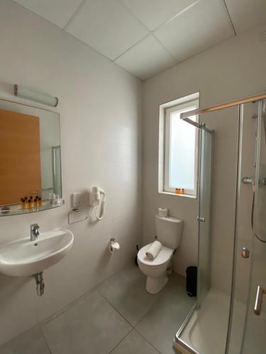 a bathroom with a toilet and a sink and a shower at Fisherman's Cove Guesthouse in Marsaxlokk
