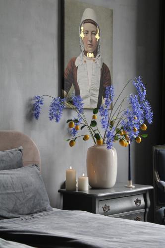 a table with a vase with blue flowers and candles at Logies aan de Dam in Middelburg