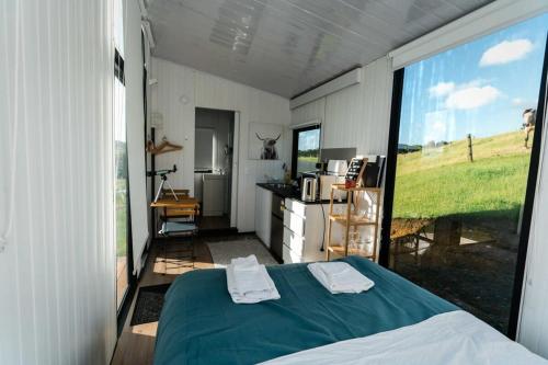 sypialnia z łóżkiem i dużym oknem w obiekcie Mighty Tiny House 1 w mieście Ruawaro