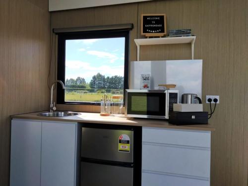 uma cozinha com um balcão com um micro-ondas e uma janela em Saffrondaze Farmstay em Oxford