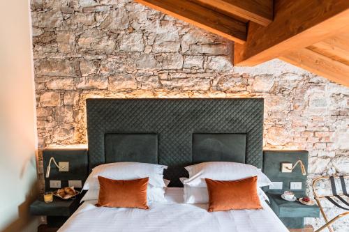 two beds in a bedroom with a stone wall at Pavillon Suite in Peschiera del Garda