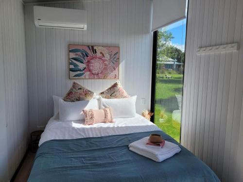 1 dormitorio con 1 cama grande y ventana grande en Deloraine Tiny Retreat en Whangarei