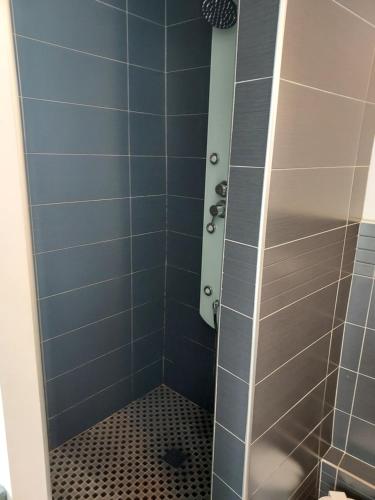 une salle de bain avec douche aux carreaux bleus dans l'établissement GITE LA BEAUTEE, à Hermanville-sur-Mer