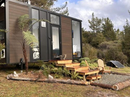 una casa pequeña con terraza y banco en Aroha Tiny House, en Rangihaeata