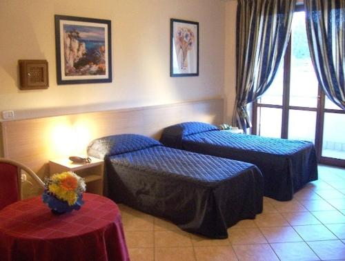 a hotel room with two beds and a table at Villa Giovanna in Somma Lombardo