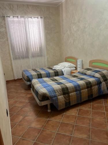 two beds in a room with a tiled floor at La Marinella in Palmi